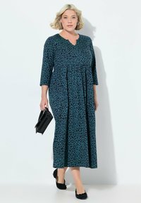 Robe maxi en teal avec imprimé léopard noir, dotée d'un décolleté en V et de manches trois-quarts, assortie à des ballerines noires et un sac à main noir.