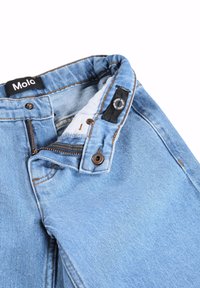Ελαφρώς μπλε τζιν από denim με ανοιχτό φερμουάρ και κουμπί, που δείχνει το λευκό εσωτερικό ύφασμα και την μαύρη ετικέτα της μάρκας "Molo" στη μέση.
