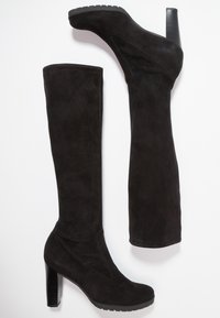 Bottes en daim noir au-dessus du genou avec un talon bloc haut. Texture lisse avec un design incurvé et des coutures avant renforcées. Semelle plate en caoutchouc.