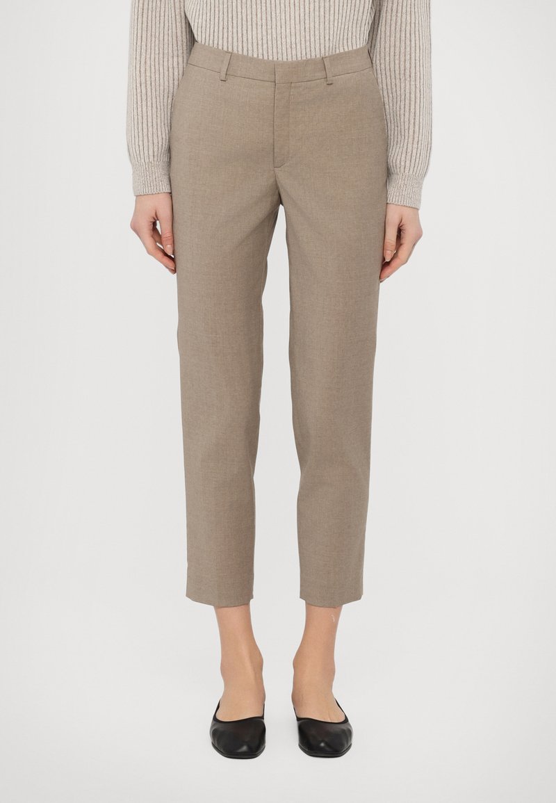 Beige housut, jotka on muotoiltu slim fit -malliseen ja kynämäiseen pituuteen, ja joissa on hienovarainen tekstuurikangas. Pariutettu mustien matalakorkoisten kenkien kanssa.