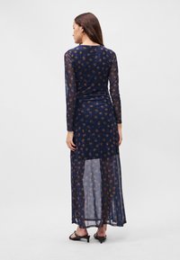 Námořnická modrá maxi šaty s dlouhými, průhlednými rukávy, květinový vzor ve světle hnědé. Mají přiléhavý korzet a splývavou, průhlednou sukni.