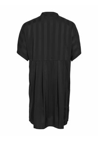 Top nero con maniche corte, caratterizzato da un motivo a righe verticali e una schiena plissettata per un tocco di texture in più. Tessuto morbido con vestibilità rilassata.