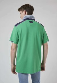 Polo vert avec un col contrastant bleu marine et bleu clair, manches courtes et une étiquette à l'arrière. Matière en coton avec une finition texturée.