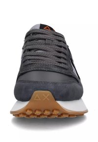Sneaker grigio con tomaia in suede e sintetico, lacci testurizzati, suola in gomma con piccoli tacchetti e intersuola bianca con accenti arancioni.