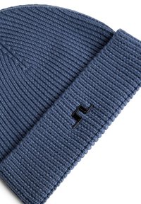 Blå stickad mössa med ribbad textur och uppvikt kant. Har en liten svart logotyp framtill. Mjuk och flexibel tyg.