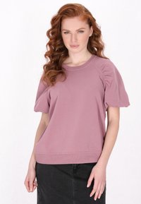 Sweatshirt scurt cu mâneci, roz deschis, cu guler rotund, mâneci cu volum texturat și croială lejeră, asociat cu o fustă din denim neagră.