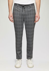 Grijze geruite broek met een trekkoord in de taille, met een gestructureerde stof en subtiele blauwe accenten, gecombineerd met witte sneakers.