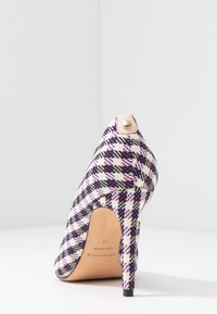 Chaussure à talon aigu avec un design en tissu à carreaux noir, blanc et violet, bout pointu et un accent beige avec un bouton en or au talon.