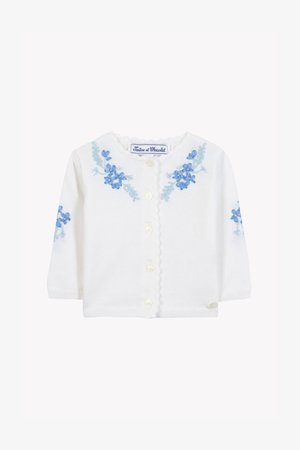 Fehér kötött kardigán hosszú ujjakkal, mindkét oldalon kék virágos hímzéssel és hullámos szegélyű gallérral. Gyöngyházgombok az elején.