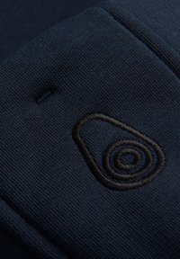 Tejido azul marino que presenta un diseño de aguacate bordado en negro con un detalle en espiral, destacando una apariencia suave y elegante.