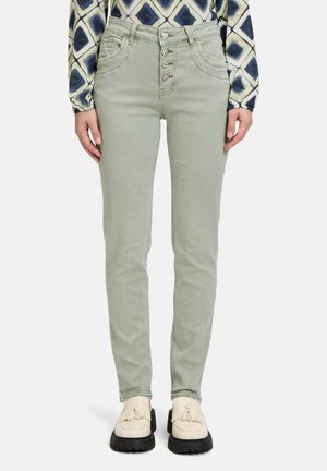 Jean en denim vert avec une taille haute, fermeture à cinq boutons et poches avant. Assortis avec des chaussures de couleur crème.