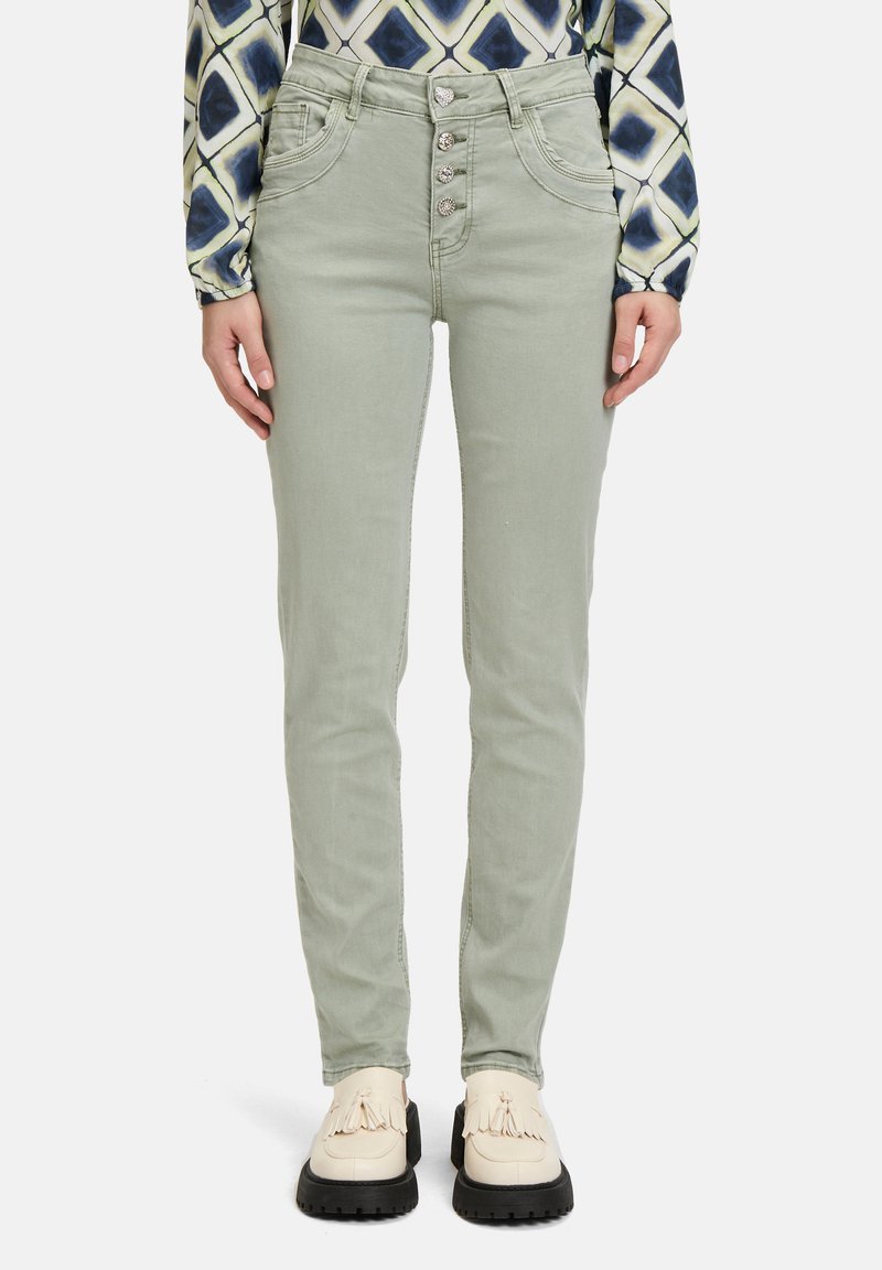 Jean en denim vert avec une taille haute, fermeture à cinq boutons et poches avant. Assortis avec des chaussures de couleur crème.