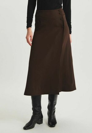 Jupe enroulée marron en tissu lisse, dotée d'une taille haute, de quatre boutons décoratifs sur un côté, et d'une silhouette évasée fluide.