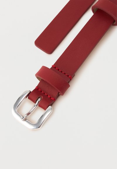 Κόκκινη δερμάτινη ζώνη με ασημένια μεταλλική αγκράφα και κόκκινες ραφές σε λευκό φόντο.