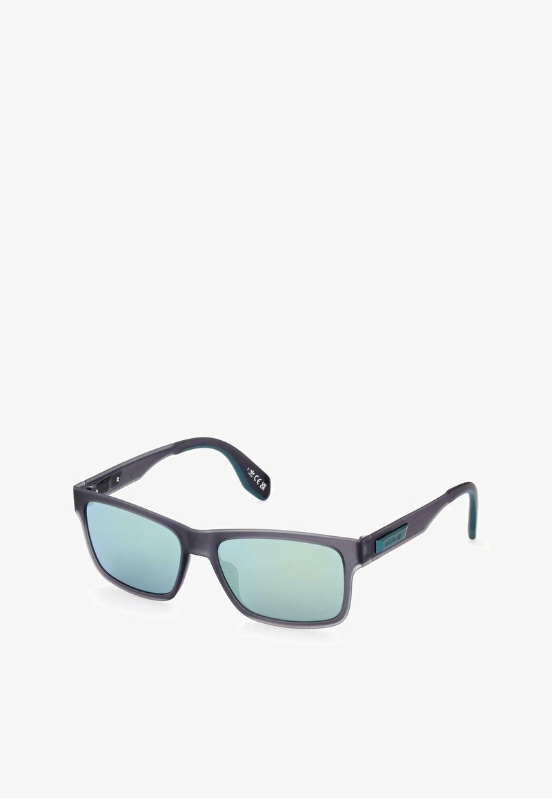 Occhiali da sole con montatura rettangolare, in plastica nera opaca, lenti gradiente blu-verdi, tempie regolabili e logo del marchio sul lato.