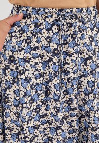 Gonna floreale blu navy con una miscela di fiori azzurri e bianchi. Presenta un elastico in vita e un cordoncino per una vestibilità regolabile.
