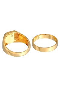 Due anelli: uno in oro lucido con bordi arrotondati e internamente piatto; l'altro ha un design spesso e angolare, con una finitura lucida, entrambi impressi con "925."