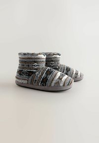 Gebreide slippers met grijze, zwarte en bruine strepen, met een zachte wol-achtige textuur en een grijze rubberen zool voor binnengebruik.