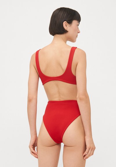 Costume da bagno rosso con texture liscia, caratterizzato da un bottom a vita alta e un top con schiena a scoperta. Colore semplice e uniforme con spalline larghe.