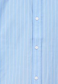 Camicia a righe azzurro chiaro in cotone. Presenta strisce verticali bianche, una patta con bottoni e bottoni bianchi. Texture liscia.