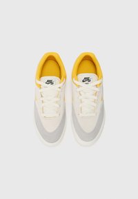 Nike SB tenisice s bež gornjim dijelom, sivi antilop akcenti, žutime oblogom i bijelim vezicama. Dizajnirane s glatkom teksturom i zaobljenim oblikom.