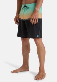 Shorts de bain pour hommes avec un dégradé de vert menthe à orange en haut, un fond noir, une taille avec cordon de serrage et des coutures décoratives.