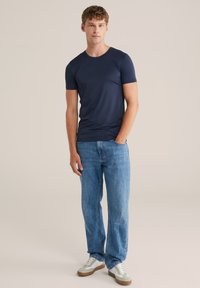 Mornarsko kratkotrajno majico z kratkimi rokavi, lahkotna tkanina, okrogla ovratnica. Združena s širokimi svetlo modrimi jeans hlačami in sivimi supergami z belimi detajli.