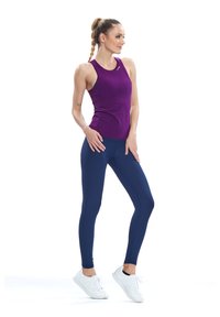 Lila ujjatlan sportos felső, ami sötétkék leggings-szel és fehér sportcipővel van párosítva. A felső kerek nyakkivágással és testhezálló szabással rendelkezik.