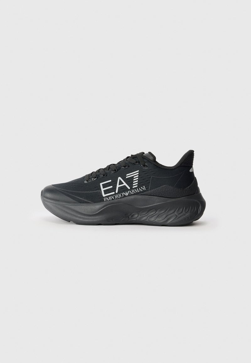 Black athletic shoe with a textured upper, featuring a thick sole and prominent white branding on the side. Lace-up design with a curved shape.