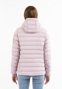 Giacca puffer rosa chiaro con sezioni a nido d'ape orizzontali, cappuccio e polsini a coste. Indossata sopra jeans chiari.