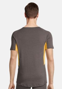 Grå kortærmet træningsshirt med gule sidelåse, rund halsudskæring og en glat tekstur. Har raglanærmer og en let buet kant.