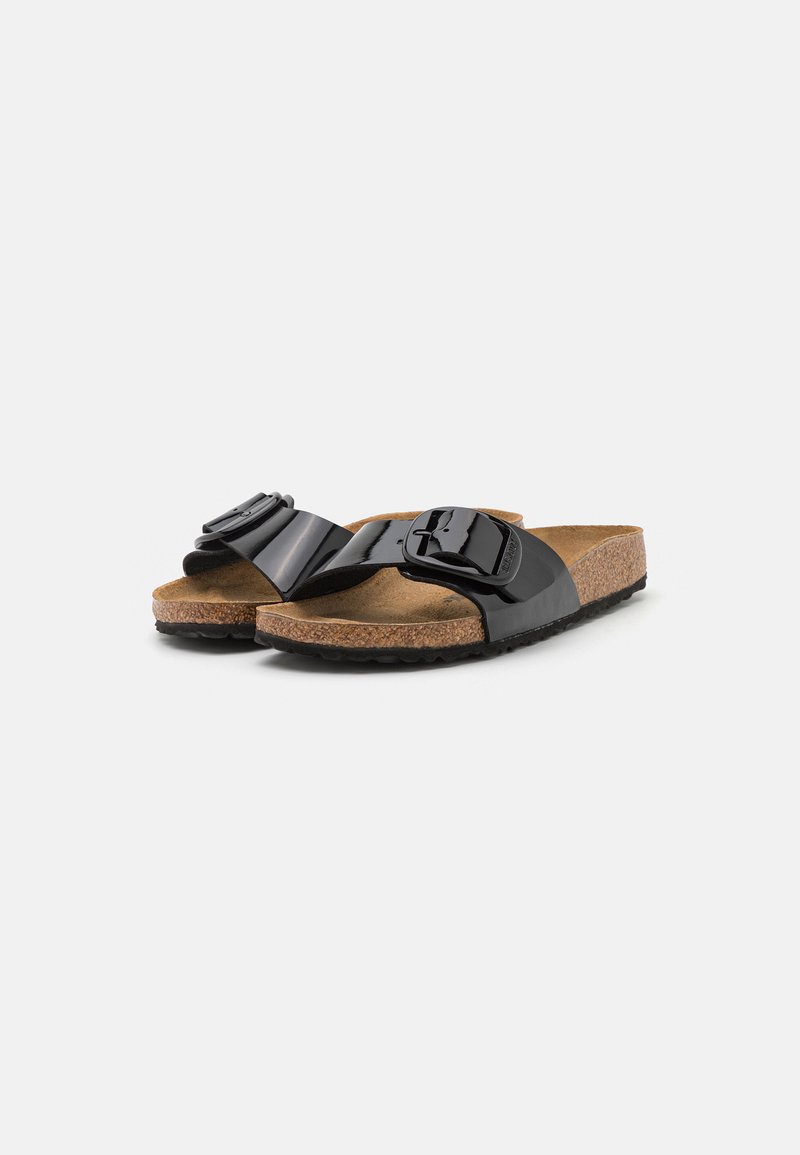 Schwarze Slipper mit Korksohlen und großen verstellbaren Schnallen oben, vor einem schlichten weißen Hintergrund dargestellt.