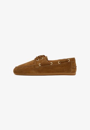 Scarpe slip-on in suede marrone con punta arrotondata, due occhielli e cuciture a contrasto. Suola in gomma con una texture liscia.