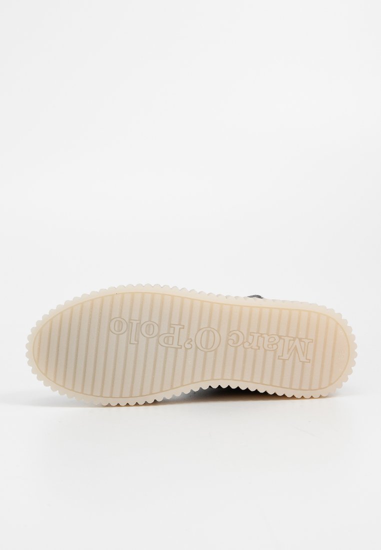 Czarne sneakersy z teksturowaną gumową podeszwą, z prążkowanym wzorem i kremową środkową podeszwą. Nazwa marki jest wytłoczona na spodzie.