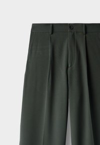 Tmavě zelené kalhoty s hladkou texturou, vybavené jedním předním knoflíkem, předními záhyby a bočními kapsami. Střihaný design.