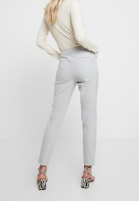 Pantalones grises ajustados con un corte slim, con bolsillos traseros. Combinados con sandalias de tacón alto con estampado de cebra y correas en el tobillo.