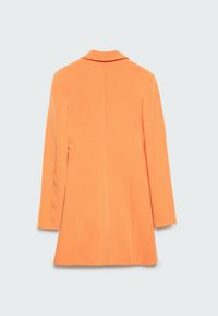 Manteau ajusté orange à manches longues avec col, vu de dos sur un fond gris clair uni.