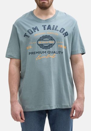 T-shirt en coton bleu clair avec col rond, manches courtes et impression de logo à l'avant affichant "Tom Tailor" et des éléments décoratifs en bleu foncé et orange.