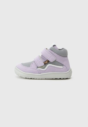 Zapatilla deportiva de caña alta para niños en color lila claro y gris, con dos tiras de velcro y suela de goma blanca sobre fondo blanco.