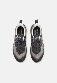 Chaussures de sport dans des nuances de gris avec une tige en mesh respirant, un embout renforcé, des lacets gris et une languette pour un enfilage facile.