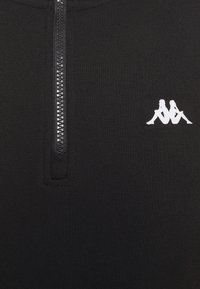 Pullover nero con mezza zip, caratterizzato da una texture morbida e liscia e un piccolo logo bianco sul lato sinistro. Design elegante e minimalista.