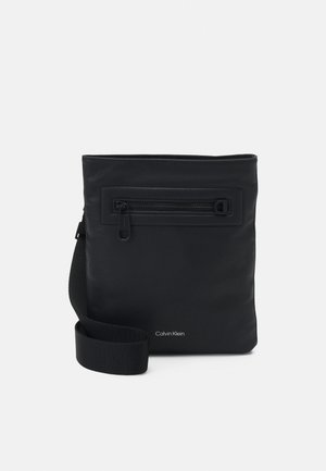 Borsa sintetica nera con tasca frontale con zip, forma rettangolare, cinturino regolabile e branding discreto nella parte inferiore. Texture liscia.