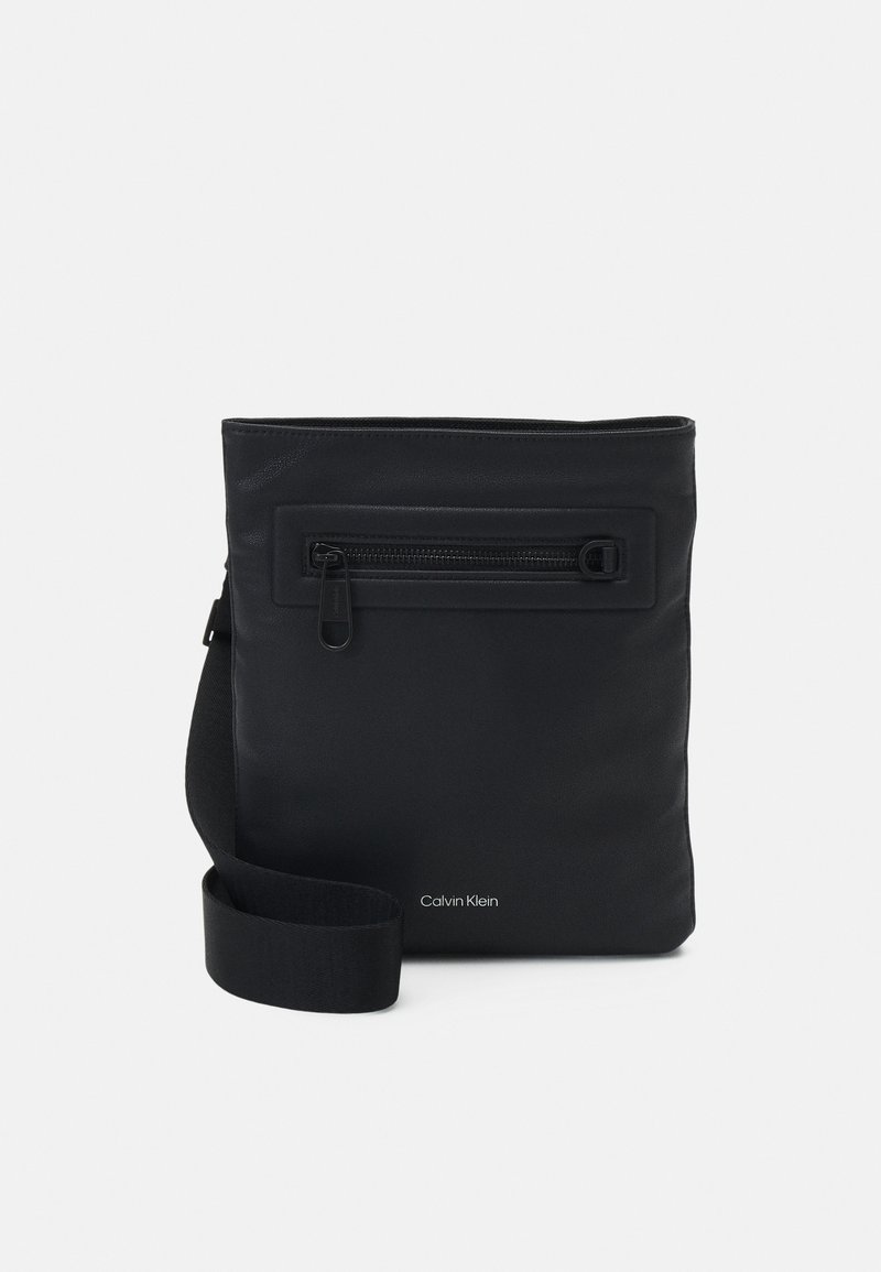 Borsa sintetica nera con tasca frontale con zip, forma rettangolare, cinturino regolabile e branding discreto nella parte inferiore. Texture liscia.