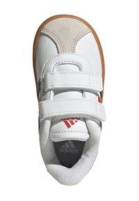 Zapatilla blanca con acentos de ante gris, parte superior de cuero, dos correas de velcro y suela de goma. Presenta detalles de logotipo en rojo y azul.