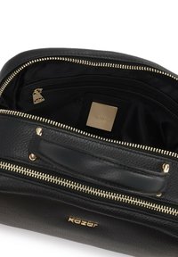 Borsa in pelle nera con hardware dorato. Presenta un materiale testurizzato, scomparti con zip e una placca con logo all'interno. Design compatto.