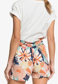 Shorts fleuris avec un motif multicolore en pêche, marine, orange et menthe. Dotés d'une large taille élastique et d'un design plissé. Fabriqués en tissu léger.
