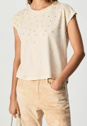 Crème-kleurige, korte mouwen, cropped t-shirt met verspreide metalen studs. Zacht katoenen materiaal, ontspannen pasvorm, afgewerkt met een ronde halslijn.