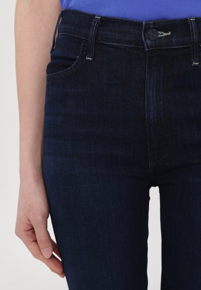 Høyt midjebånd, mørkeblå denim jeans med en glatt tekstur, tonede sømmer, og et klassisk fem-lommers design. Metallknapp i midjen.