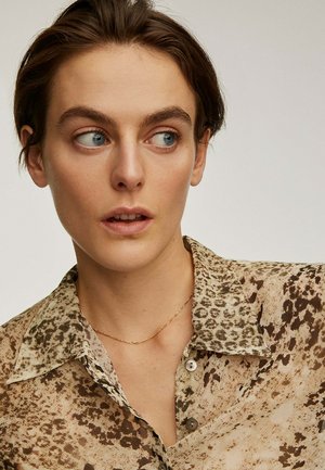 Camisa de estampado de leopardo en beige y marrón; tela ligera, diseño abotonado, cuello puntiagudo y sutil brillo. Acento de collar dorado.