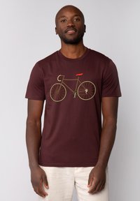 Bordeaux katoenen t-shirt met een fietsafbeelding in aardetinten en een rode zitting. Korte mouwen en een ronde halslijn.